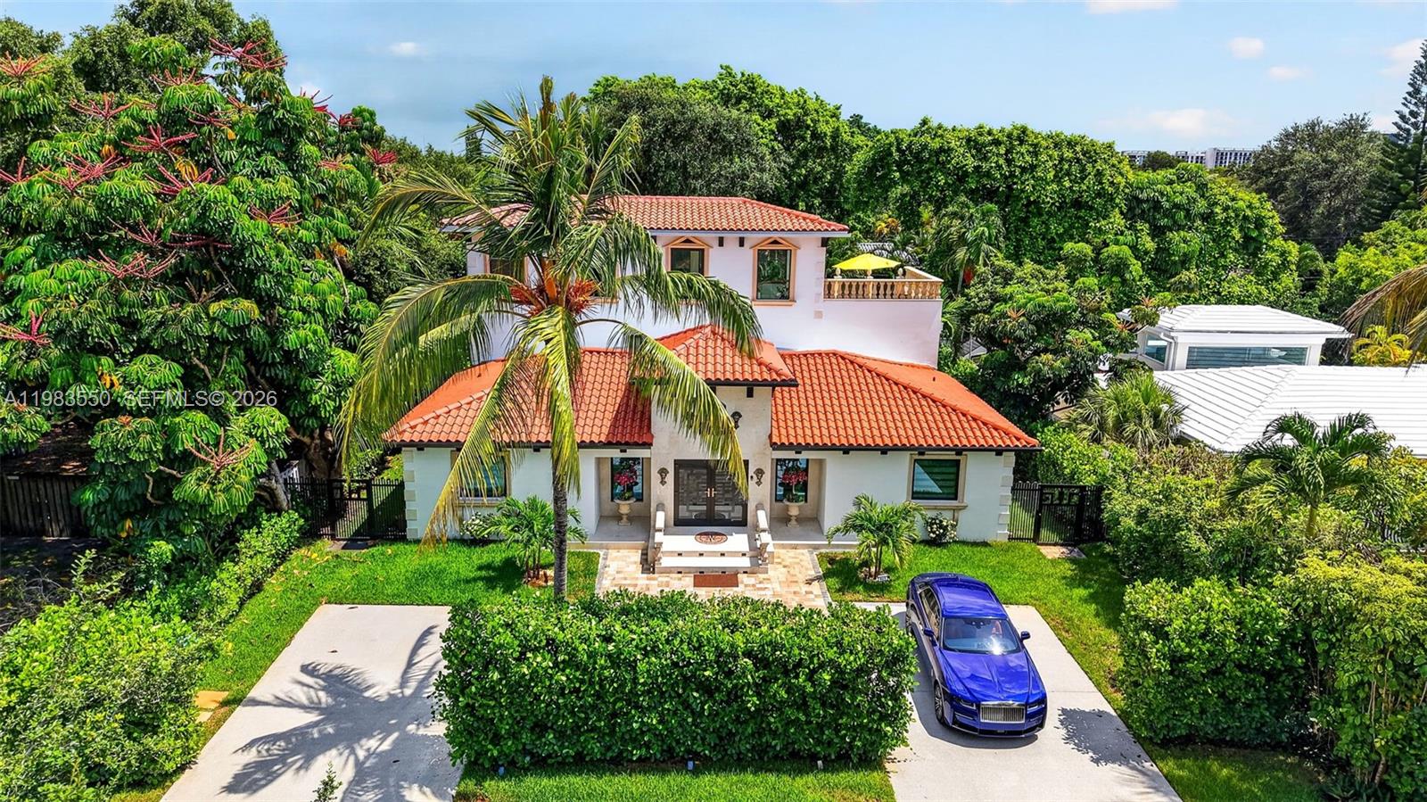 A two-story Mediterranean-style house with a red tile roof and a blue car parked outside — 941 NE 119th St, Biscayne Park FL 33161, BISCAYNE PARK, FL
