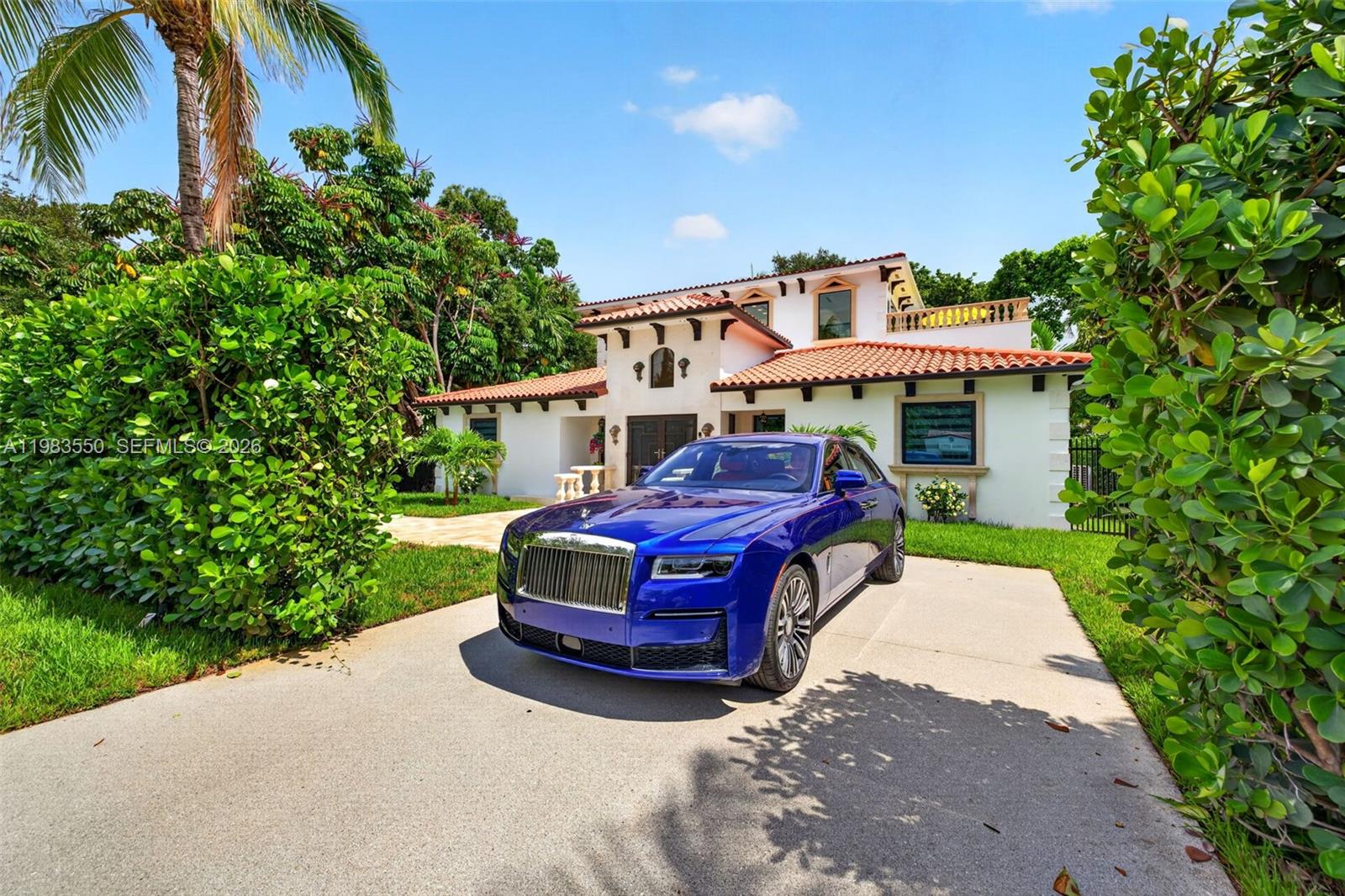 A blue Rolls-Royce is parked in the driveway of a two-story Mediterranean-style house — 941 NE 119th St, Biscayne Park FL 33161, BISCAYNE PARK, FL