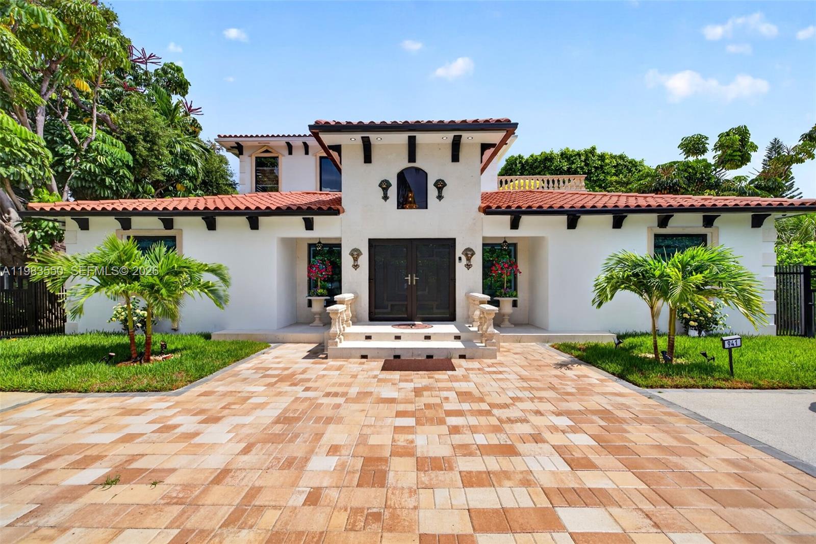 A two-story Mediterranean-style house features a tiled roof, white stucco walls, and a paved driveway — 941 NE 119th St, Biscayne Park FL 33161, BISCAYNE PARK, FL
