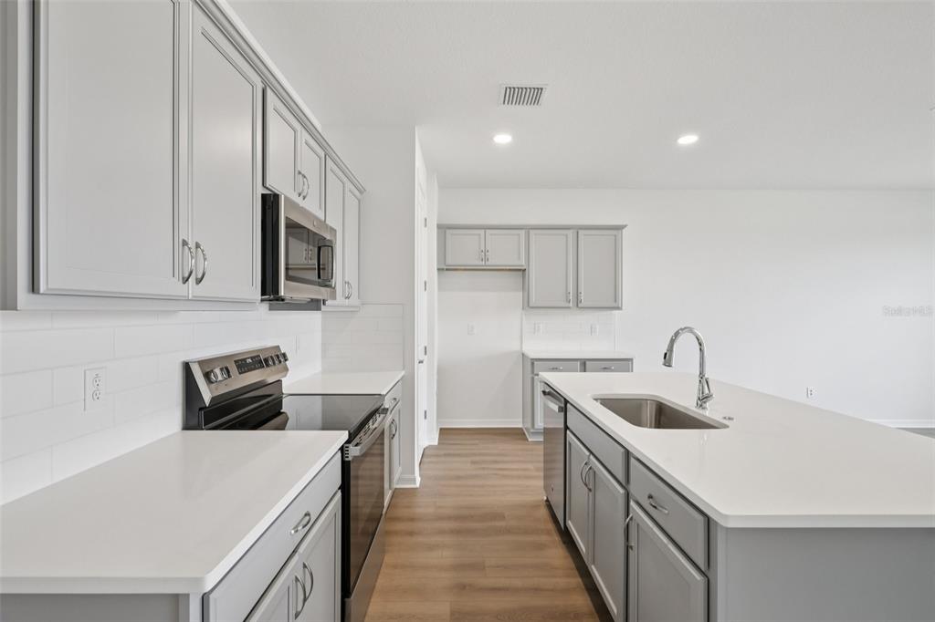 A modern kitchen features gray cabinets, white countertops, stainless steel appliances, and a central island — 31477 SPANISH MISSION ROAD, SAN ANTONIO, FL