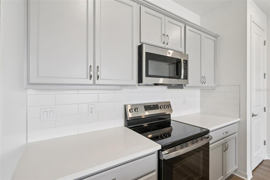 A kitchen features light gray cabinets, white countertops, a subway tile backsplash, and stainless appliances — 31477 SPANISH MISSION ROAD, SAN ANTONIO, FL