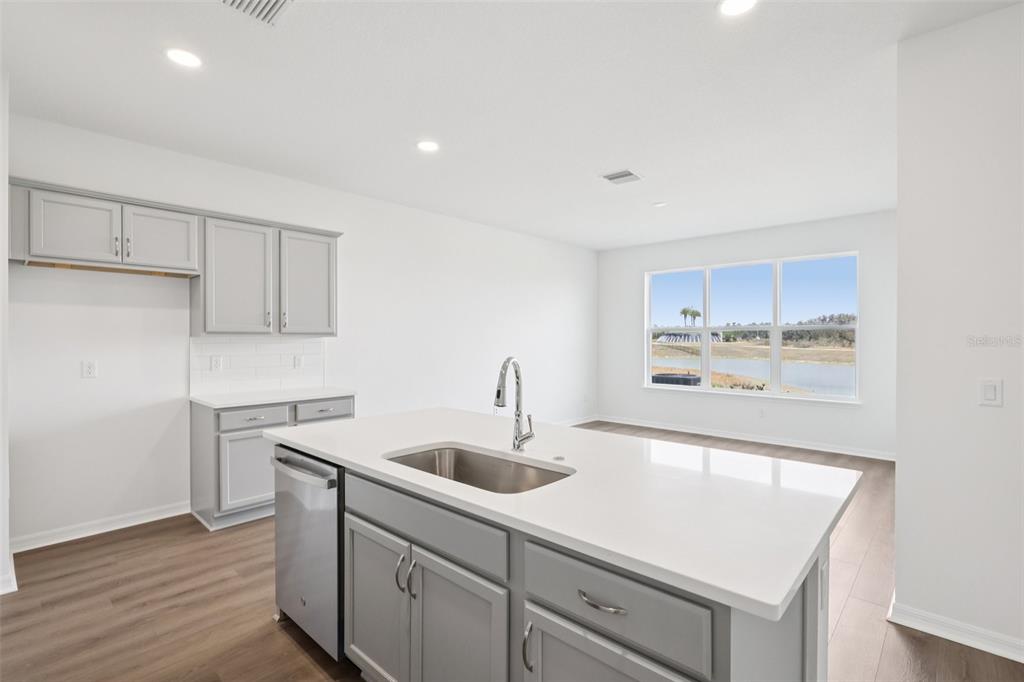 A kitchen with gray cabinets, a white island, and a view of a pond outside — 31477 SPANISH MISSION ROAD, SAN ANTONIO, FL