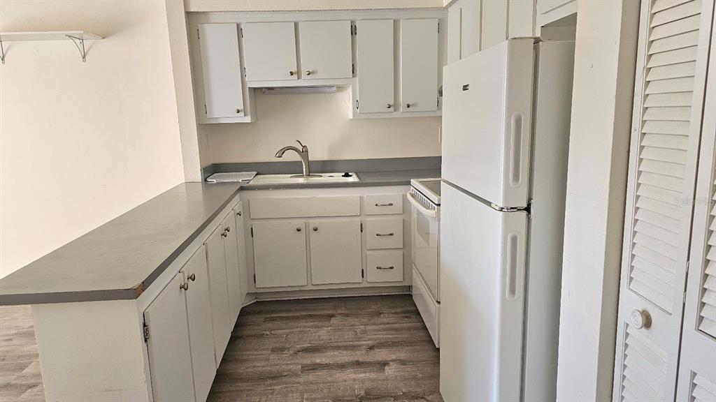 A kitchen features white cabinets, gray countertops, a white refrigerator, and wood-look flooring — 21150 GERTRUDE AVENUE UNIT 2, PORT CHARLOTTE, FL
