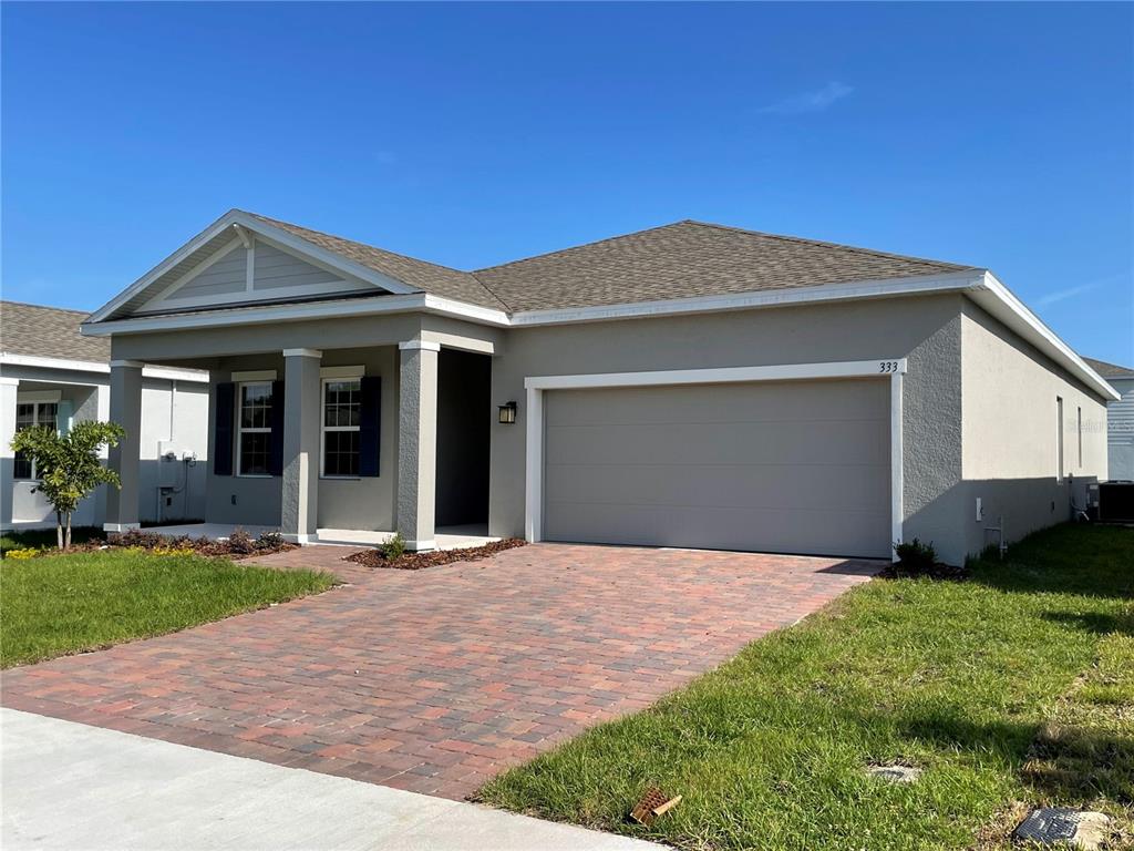 A single-story house with a gray stucco exterior, a brick paver driveway, and a two-car garage — 333 WINTER BLISS LANE, MOUNT DORA, FL