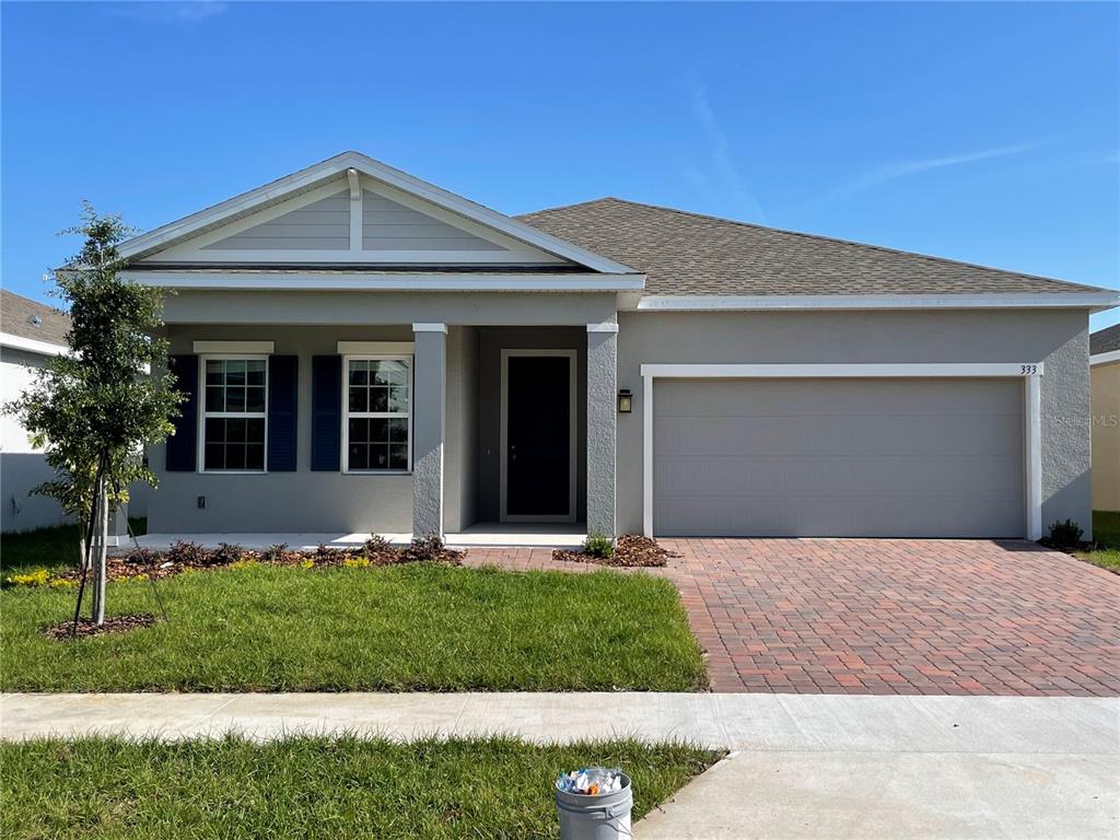 A single-story house with a gray stucco exterior, a brick driveway, and a two-car garage — 333 WINTER BLISS LANE, MOUNT DORA, FL