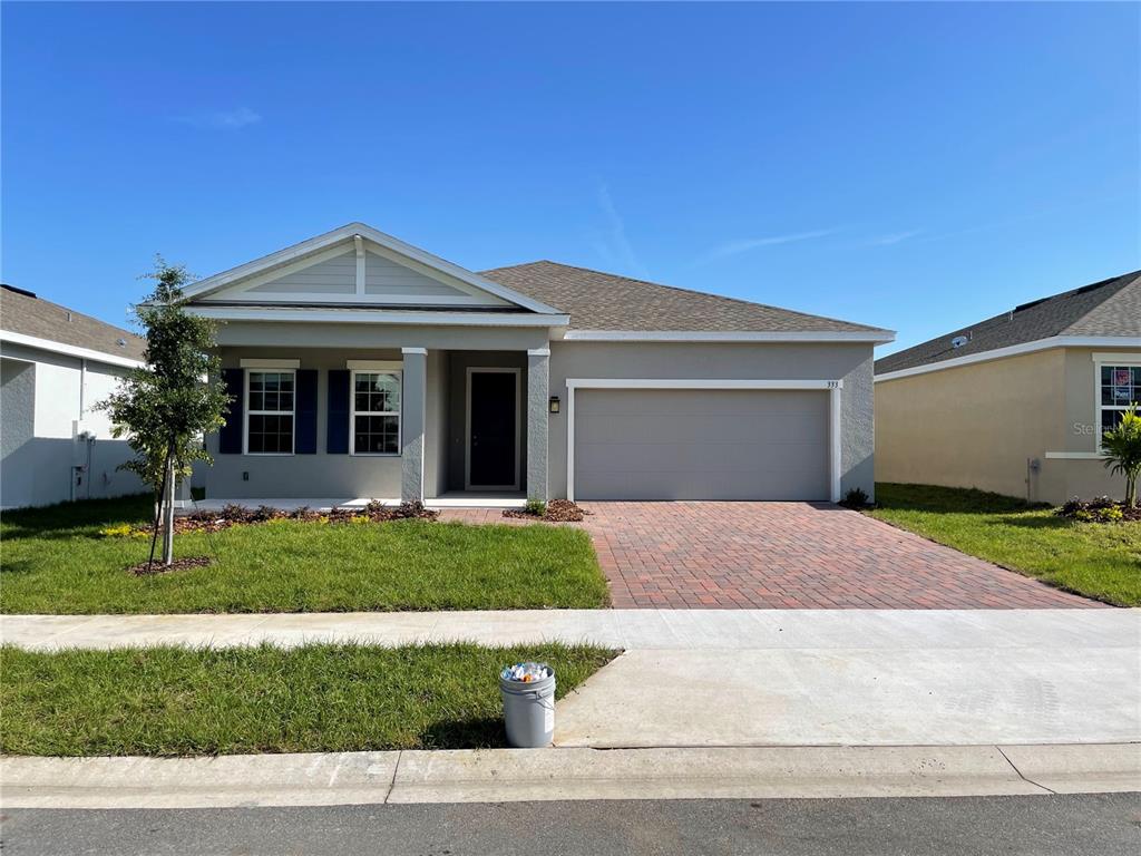 A single-story house with a gray exterior, a two-car garage, and a brick paver driveway — 333 WINTER BLISS LANE, MOUNT DORA, FL