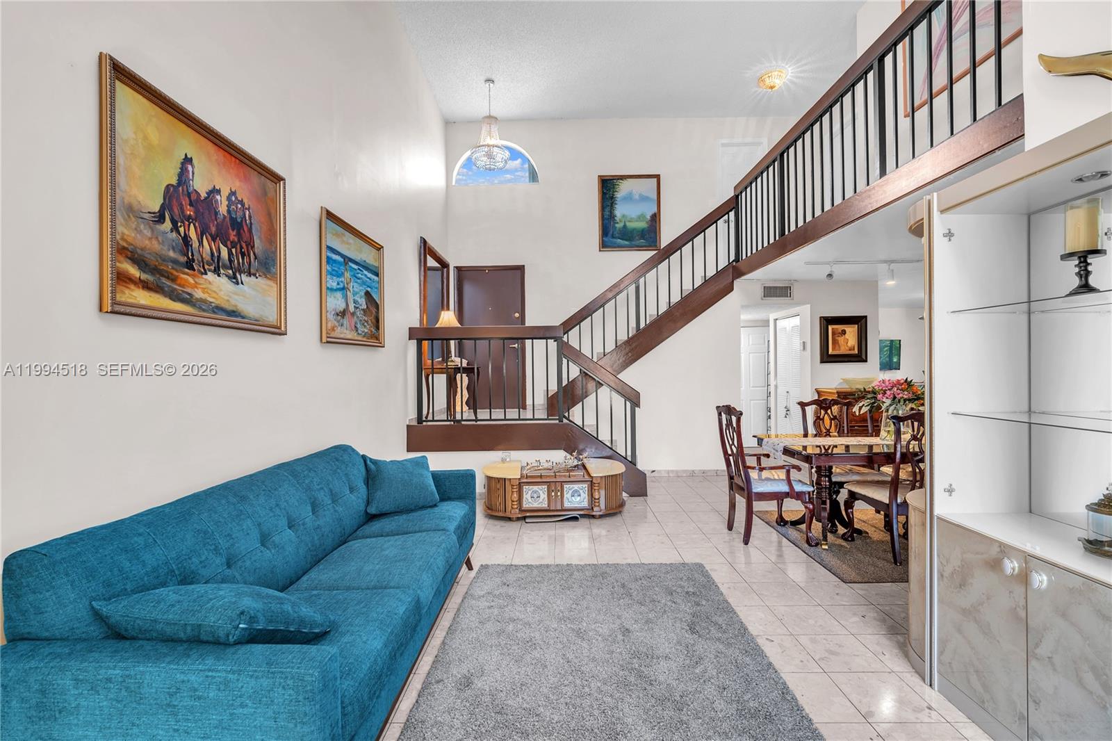 A living and dining area features a blue sofa, tiled floors, and a wooden staircase — 1321 SW 124th Ct # A, Miami FL 33184, MIAMI, FL