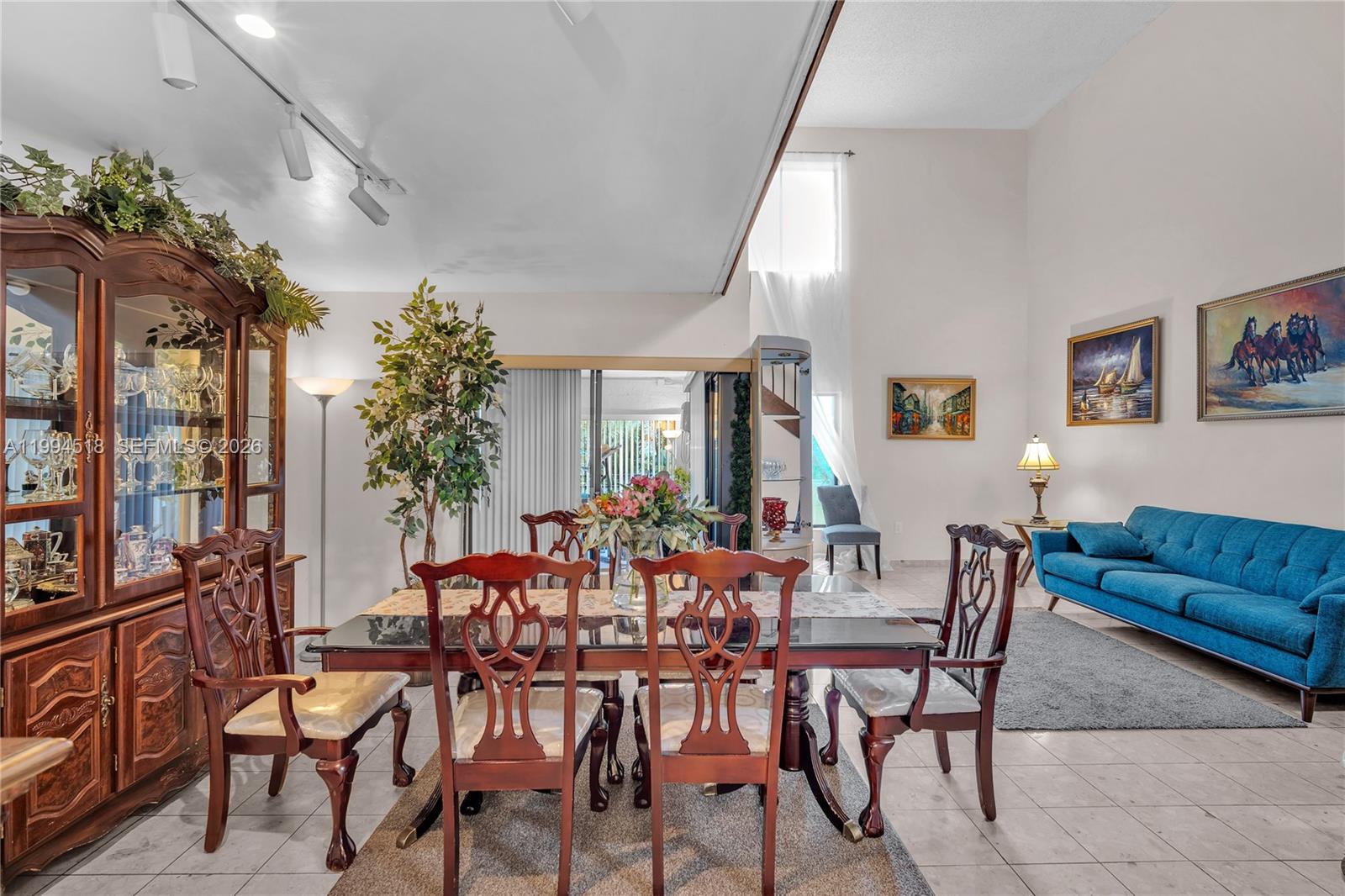 A dining area with a wooden hutch and table set sits beside a blue sofa — 1321 SW 124th Ct # A, Miami FL 33184, MIAMI, FL