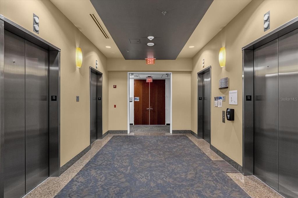 An elevator lobby features four stainless steel elevator doors, beige walls, and a patterned carpet — 189 S ORANGE AVENUE UNIT 1570, ORLANDO, FL