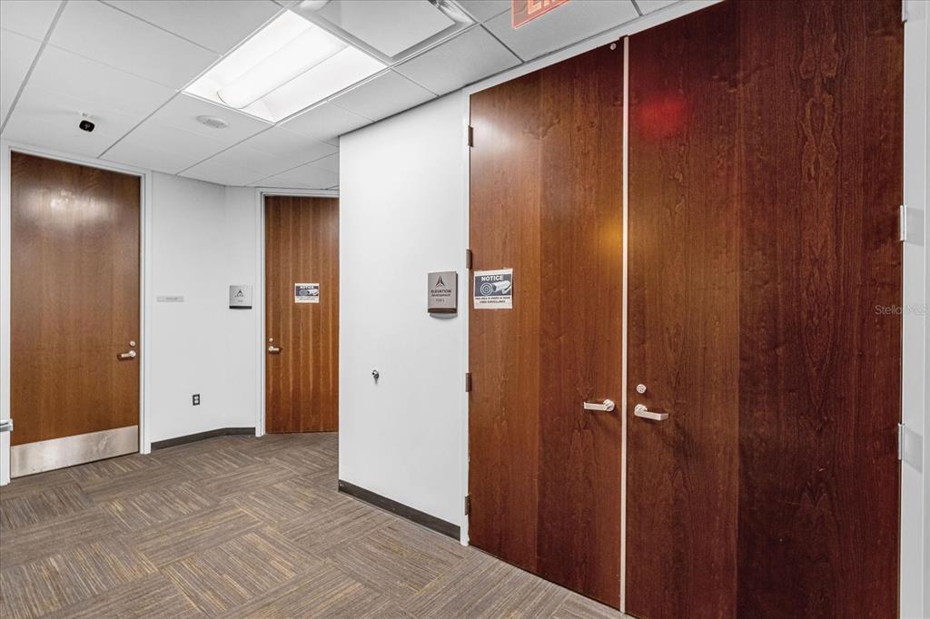A commercial hallway features wood-veneer doors, white walls, and carpeted flooring under drop ceiling tiles — 189 S ORANGE AVENUE UNIT 1570, ORLANDO, FL