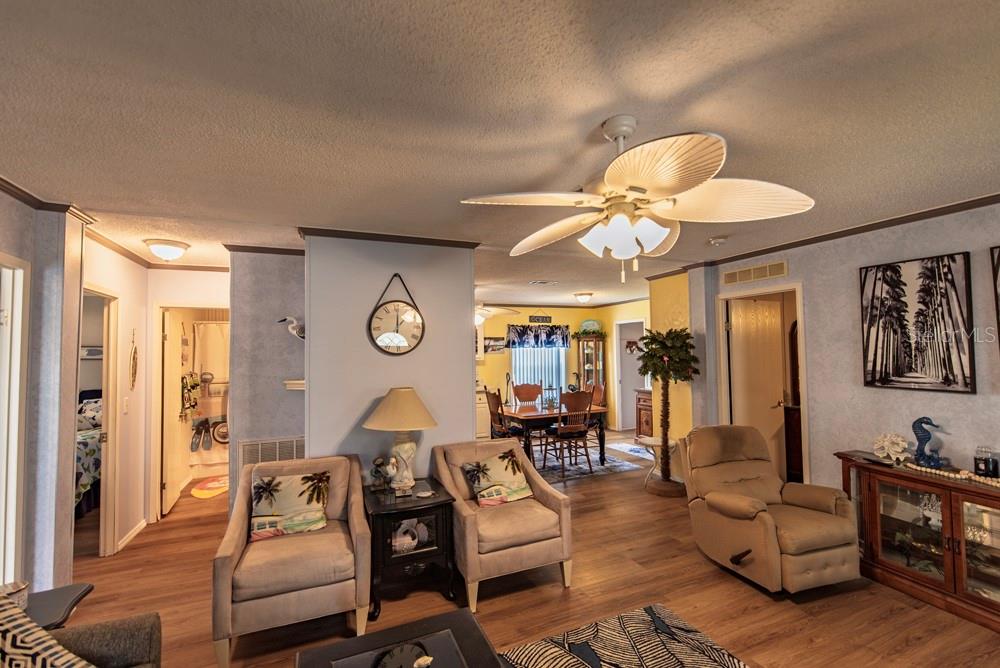 A living room with light-colored armchairs, a recliner, wood-look flooring, and a ceiling fan — 51 AMSTERDAM AVENUE, PUNTA GORDA, FL