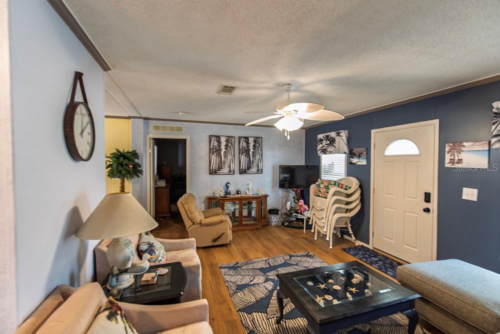 A living room features wood-look flooring, a ceiling fan, blue walls, and a glass-topped coffee table — 51 AMSTERDAM AVENUE, PUNTA GORDA, FL