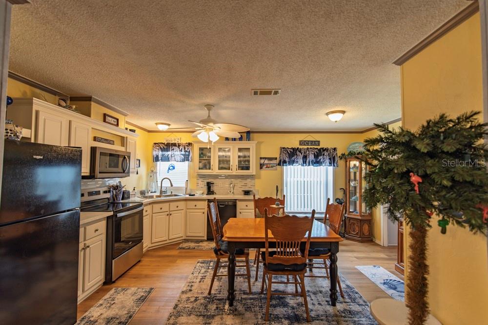 A kitchen and dining area with white cabinets, stainless appliances, and a wooden dining table — 51 AMSTERDAM AVENUE, PUNTA GORDA, FL