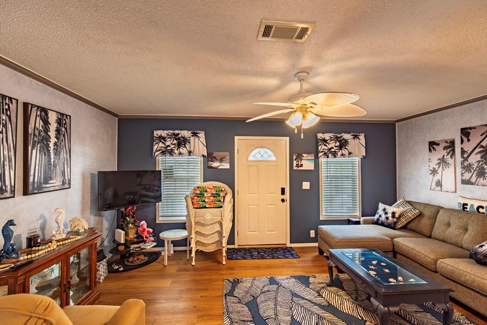 A living room features blue walls, a ceiling fan, a sectional sofa, and wood flooring — 51 AMSTERDAM AVENUE, PUNTA GORDA, FL