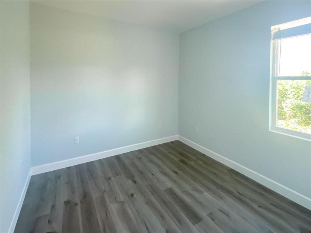 An empty bedroom features light blue walls, white trim, and gray wood-look flooring — 9163 AGATE STREET UNIT 9163, PORT CHARLOTTE, FL