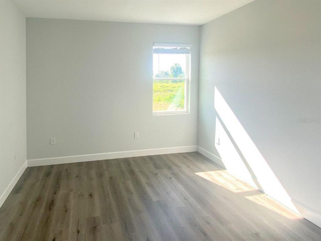 An empty bedroom features light gray walls, wood-look flooring, and a single window — 9163 AGATE STREET UNIT 9163, PORT CHARLOTTE, FL