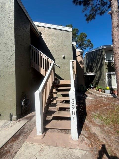An exterior view of a multi-story apartment building with wooden stairs leading to an upper unit — 5981 WINDHOVER DRIVE UNIT A10, ORLANDO, FL