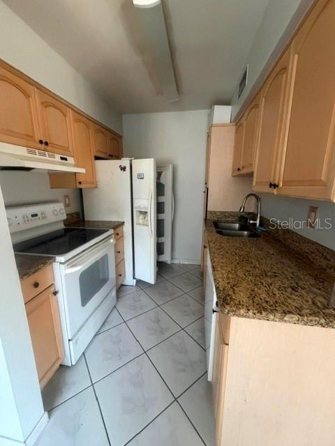 A kitchen features light wood cabinets, granite countertops, white appliances, and tiled flooring — 5981 WINDHOVER DRIVE UNIT A10, ORLANDO, FL