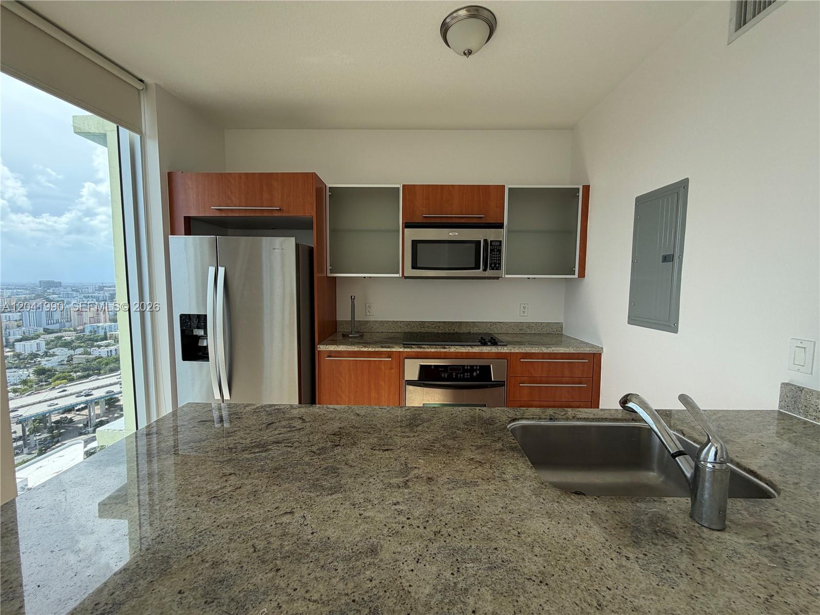 A kitchen features wood cabinets, stainless steel appliances, granite countertops, and a city view — 185 SW 7th St # 3200, Miami FL 33130, MIAMI, FL