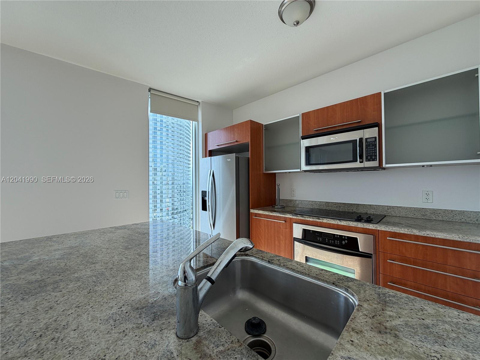 A kitchen features granite countertops, wood cabinets, stainless steel appliances, and a view of a skyscraper — 185 SW 7th St # 3200, Miami FL 33130, MIAMI, FL