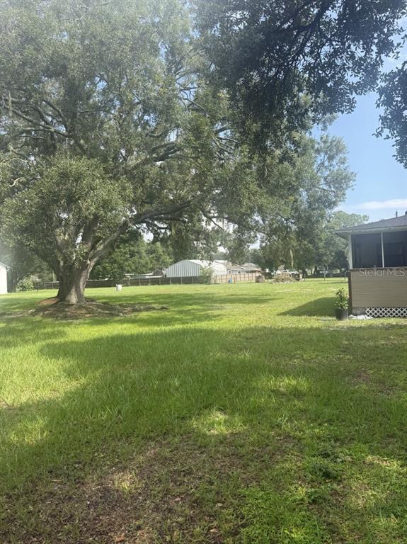 A large grassy backyard features a mature oak tree and a house with a porch — 275 TEMPLE STREET, MULBERRY, FL