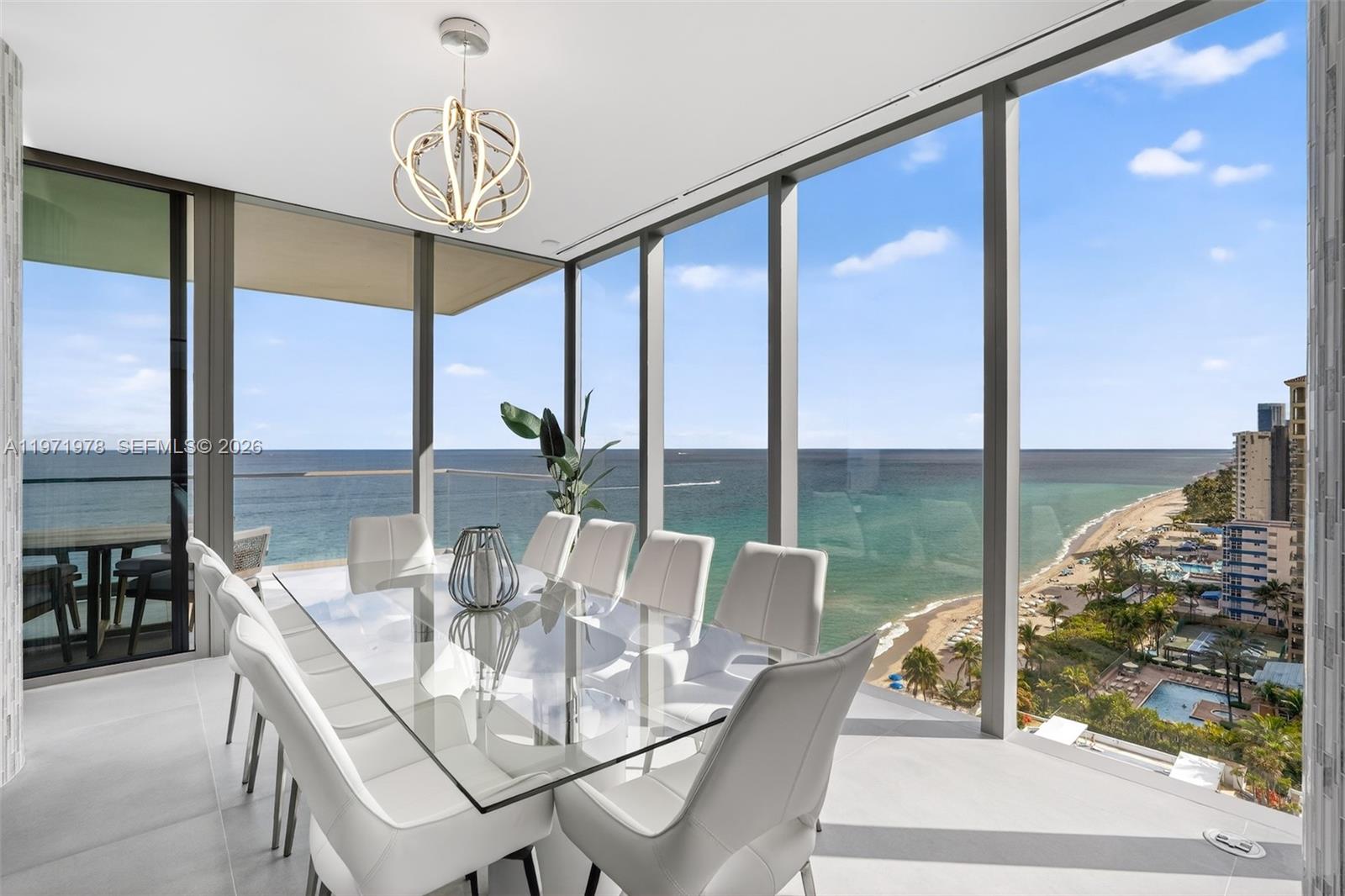 A modern dining room features a glass table, white chairs, and floor-to-ceiling ocean views — 2000 S Ocean Dr # 14B, Hallandale Beach FL 33009, HALLANDALE BEACH, FL