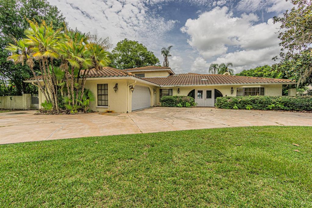 A single-story house with a tile roof, stucco exterior, and a large concrete driveway — 18129 CRAWLEY ROAD, ODESSA, FL