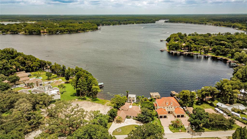 An aerial view shows waterfront homes with docks and boat slips along a large lake — 18129 CRAWLEY ROAD, ODESSA, FL
