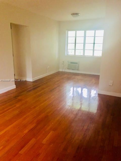 An empty room with hardwood floors, a window, and a wall-mounted air conditioning unit — 1008 E Ponce De Leon Blvd # 3, Coral Gables FL 33134, CORAL GABLES, FL