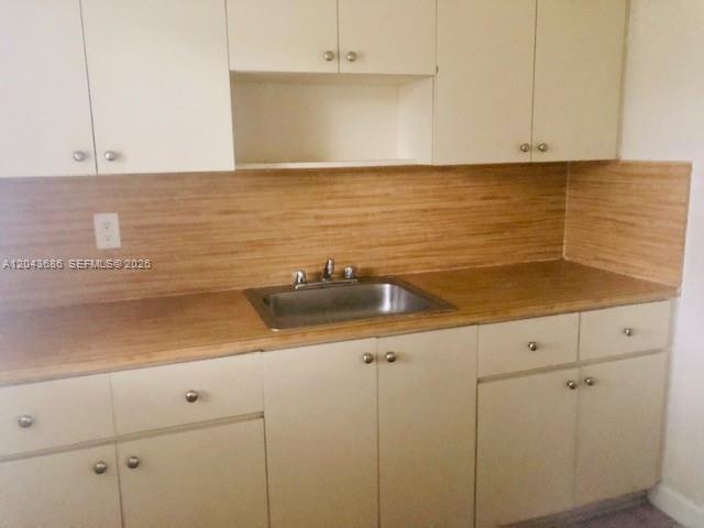 A kitchen features light-colored cabinets, a stainless steel sink, and a wood-look backsplash — 1008 E Ponce De Leon Blvd # 3, Coral Gables FL 33134, CORAL GABLES, FL