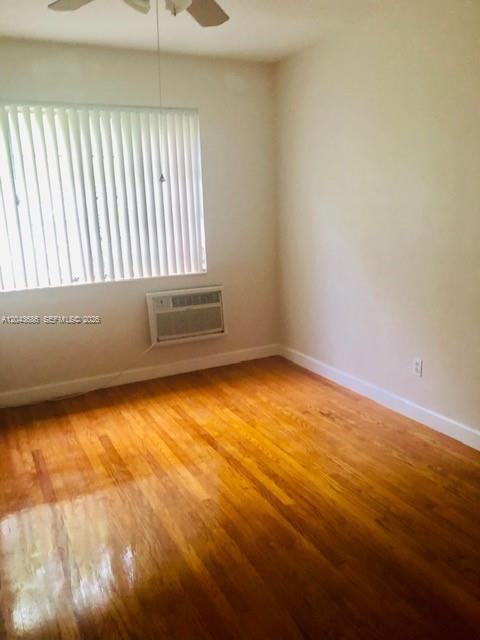 An empty room features hardwood floors, a ceiling fan, and a window air conditioning unit — 1008 E Ponce De Leon Blvd # 3, Coral Gables FL 33134, CORAL GABLES, FL