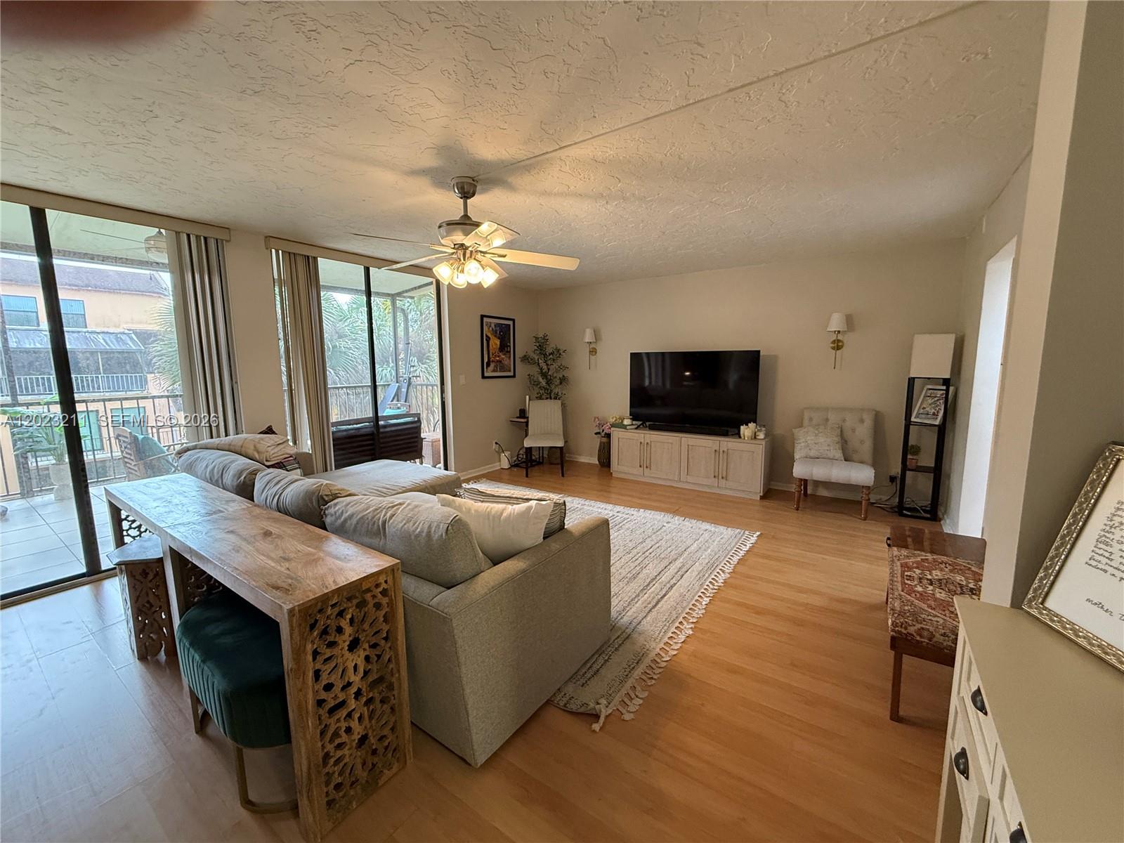 A living room features a grey sectional sofa, a wooden console table, and a television console — 450 Commodore Dr # 306, Plantation FL 33325, PLANTATION, FL