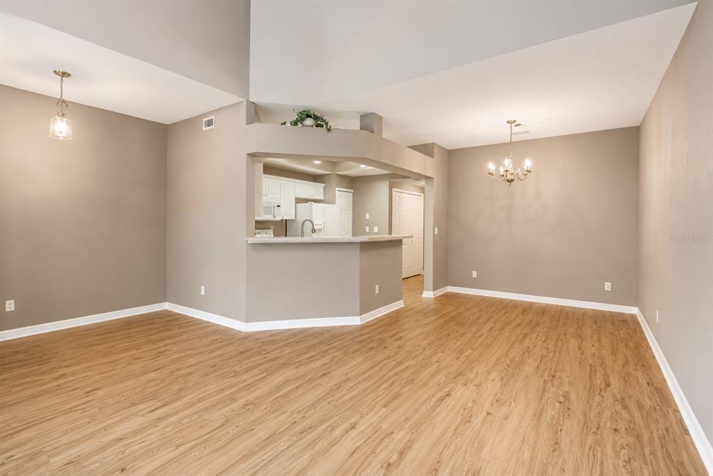 An open-concept living area features light wood-look flooring, neutral walls, and a kitchen breakfast bar — 4946 NW 1ST PLACE, GAINESVILLE, FL
