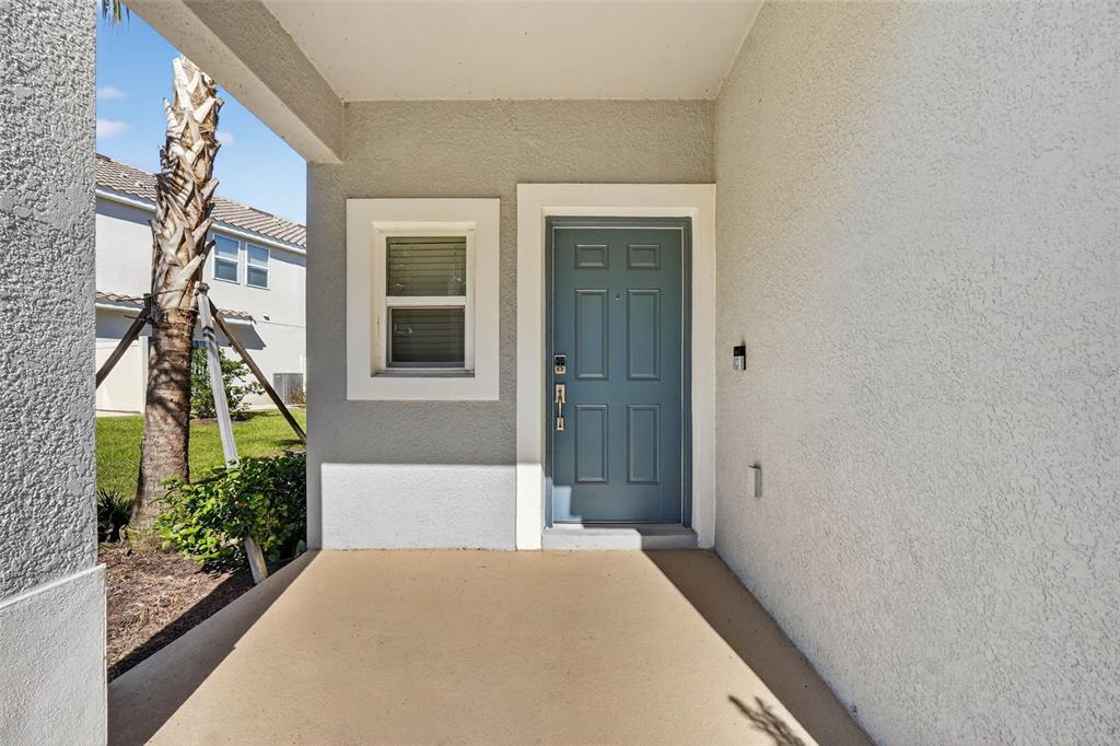 A covered concrete porch features a blue front door and a single window — 3607 MAIN HARBOR DRIVE S, KISSIMMEE, FL