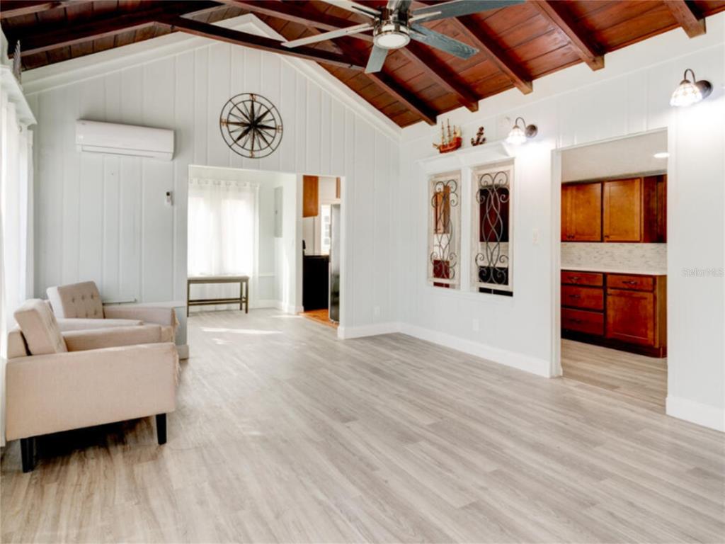 A living room with vaulted wood-beamed ceilings, light wood flooring, and an adjacent kitchen — 425 N OLEANDER AVENUE, DAYTONA BEACH, FL