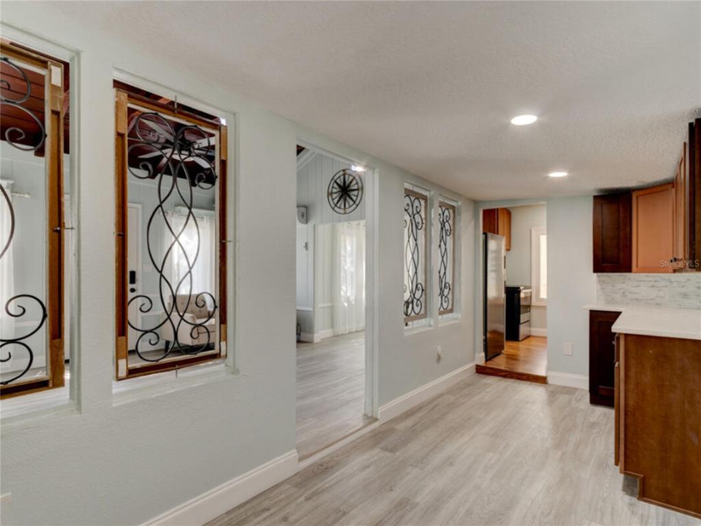 A kitchen area features light wood-look flooring, dark cabinetry, and decorative metal window inserts — 425 N OLEANDER AVENUE, DAYTONA BEACH, FL