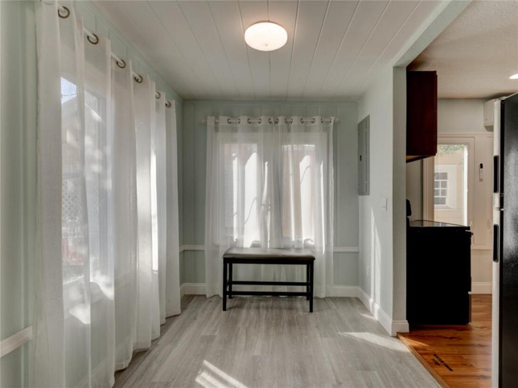 A dining area features light wood-look flooring, white paneled ceilings, and sheer curtains over windows — 425 N OLEANDER AVENUE, DAYTONA BEACH, FL