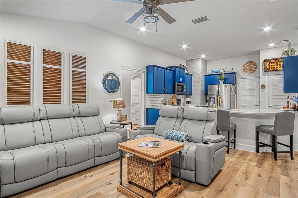 A living room with gray leather sofas and a kitchen featuring blue cabinets — 771 TUPELO CIRCLE, COCOA, FL