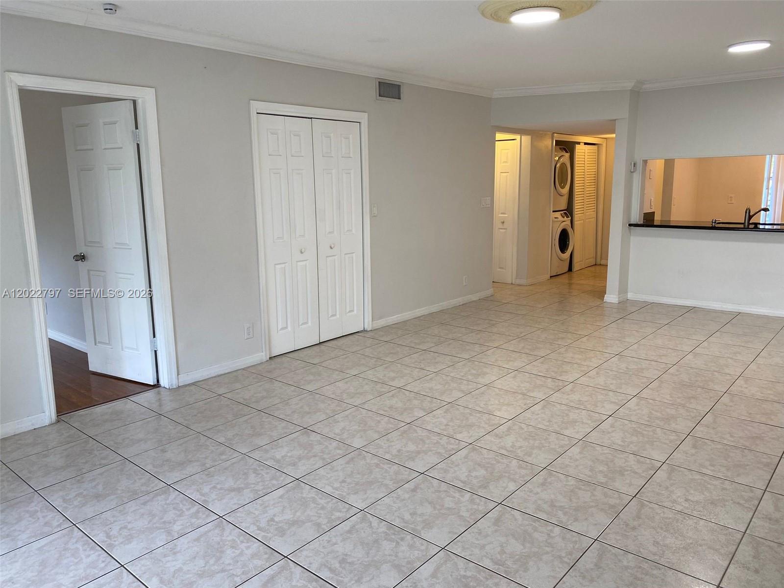 A tiled living area features a doorway, a closet, and a view into a laundry space — 4291 NW 9th Ave # 202, Deerfield Beach FL 33064, DEERFIELD BEACH, FL