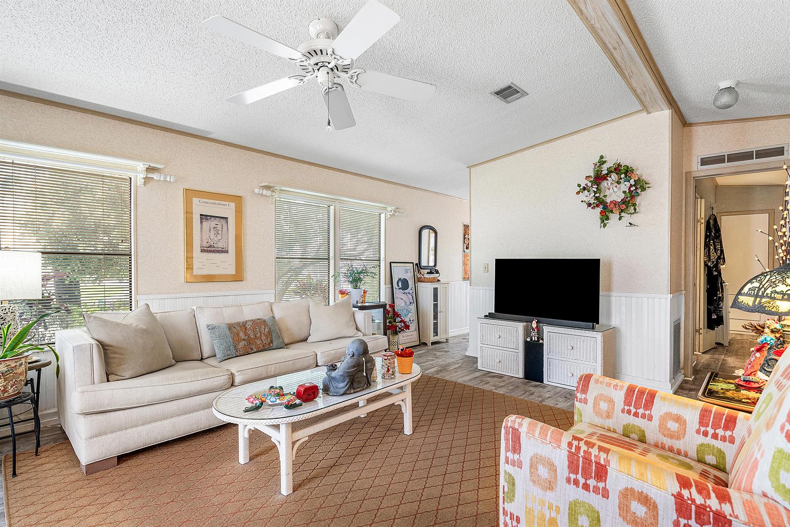 A living room features a beige sofa, patterned armchair, white coffee table, and television — 4 East Cedar Drive, Briny Breezes FL 33435, BRINY BREEZES, FL