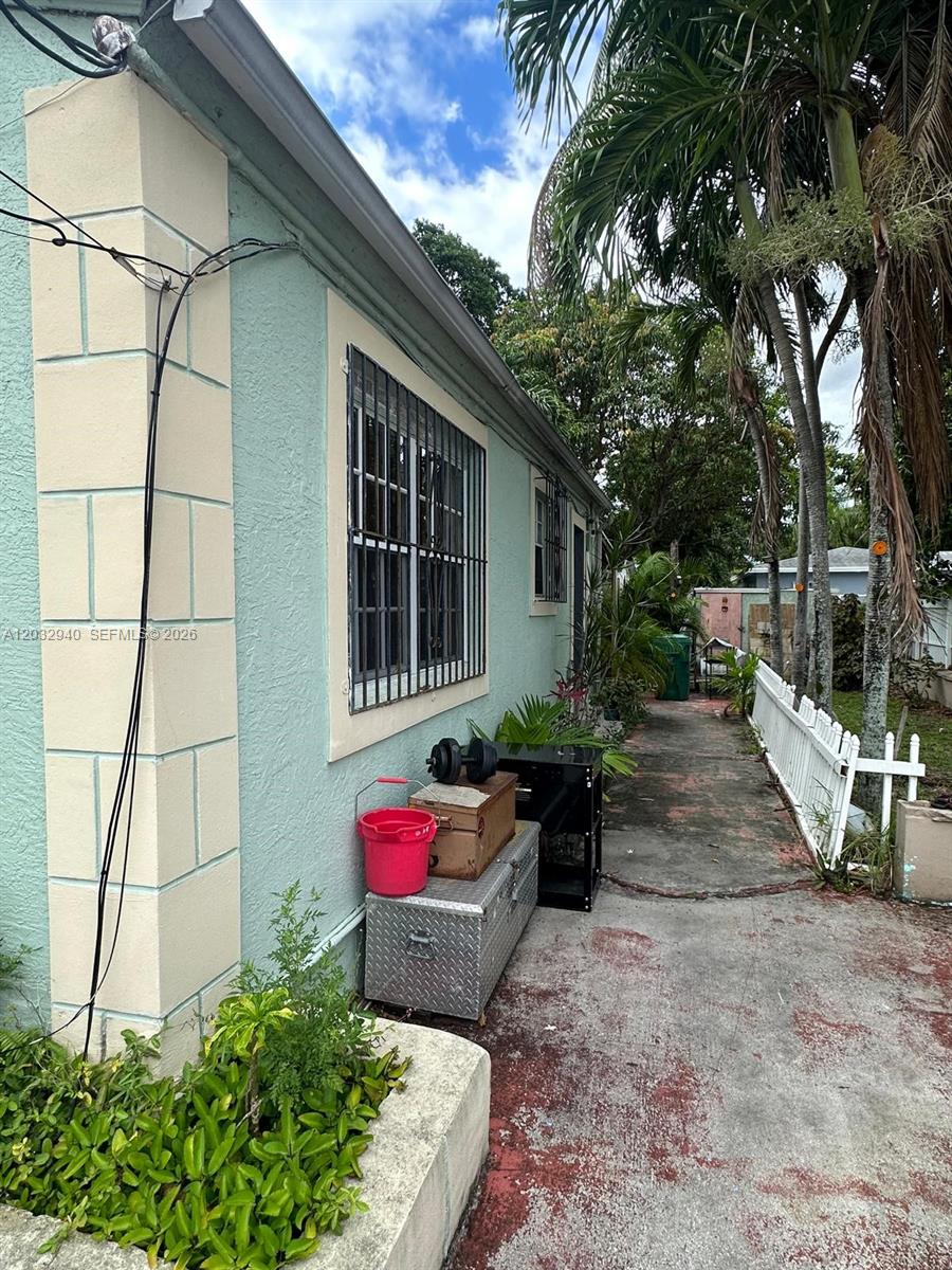 A side view of a light green house with a concrete walkway and metal storage boxes — 1376 NW 45th St, Miami FL 33142, MIAMI, FL
