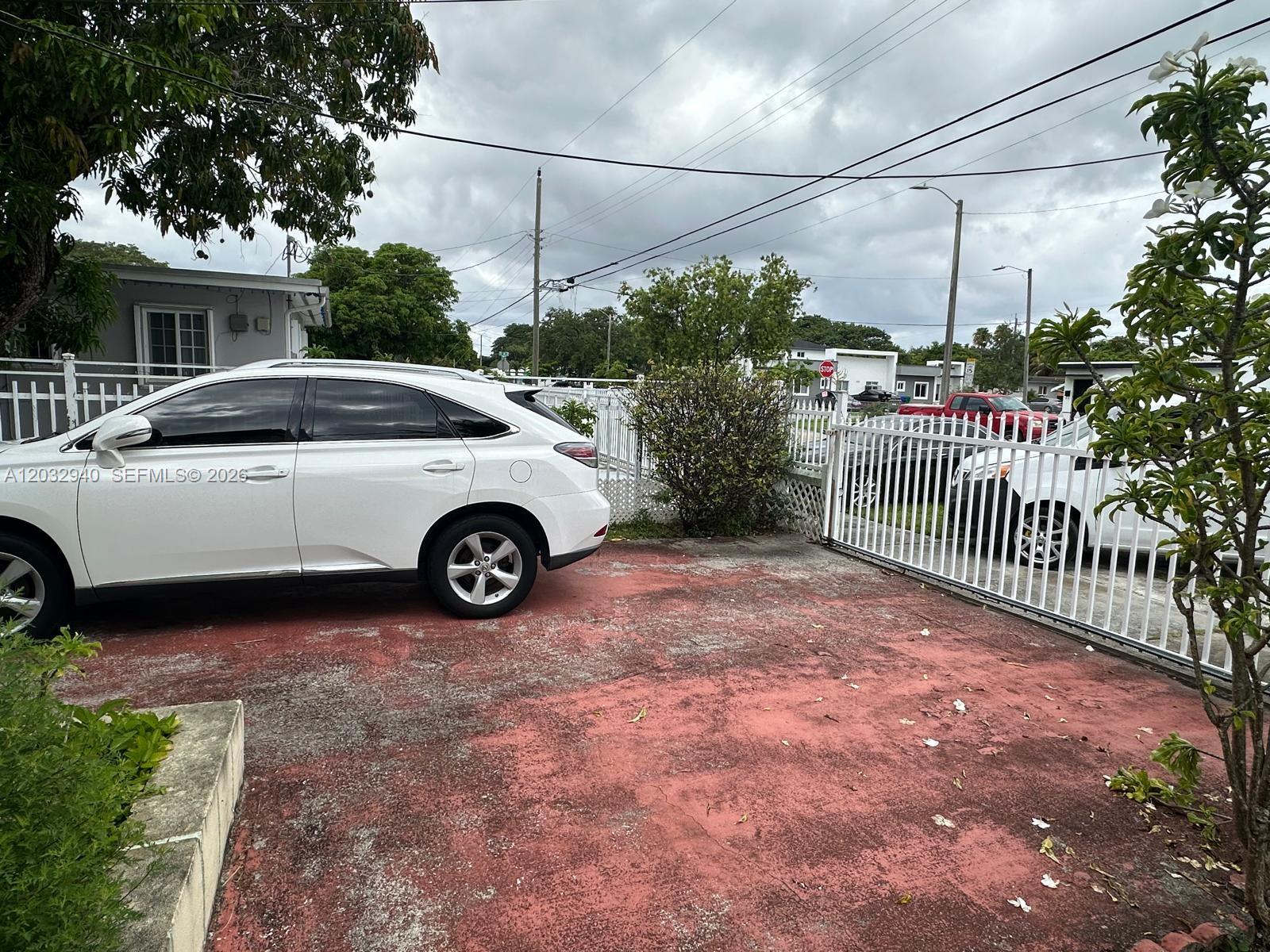 A white SUV is parked on a red concrete driveway behind a white metal gate — 1376 NW 45th St, Miami FL 33142, MIAMI, FL