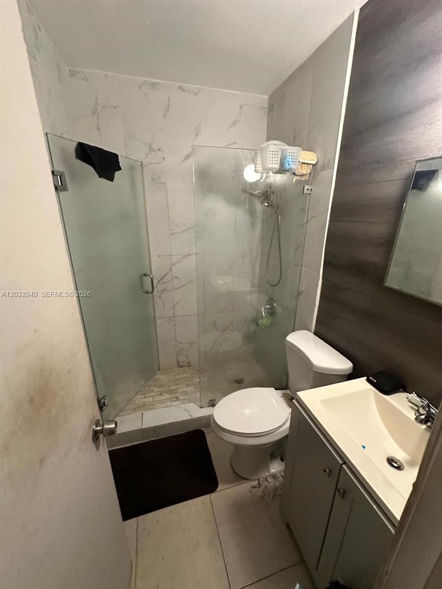 A bathroom features a glass-enclosed shower, a white toilet, and a small vanity cabinet — 1376 NW 45th St, Miami FL 33142, MIAMI, FL