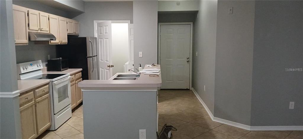 A kitchen features light wood cabinets, white appliances, a breakfast bar, and tile flooring — 5606 PINNACLE HEIGHTS CIRCLE UNIT 306, TAMPA, FL