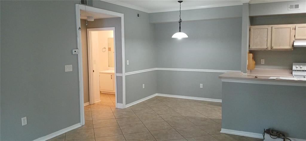 A dining area with gray walls, chair rail molding, tile flooring, and a hanging light fixture — 5606 PINNACLE HEIGHTS CIRCLE UNIT 306, TAMPA, FL
