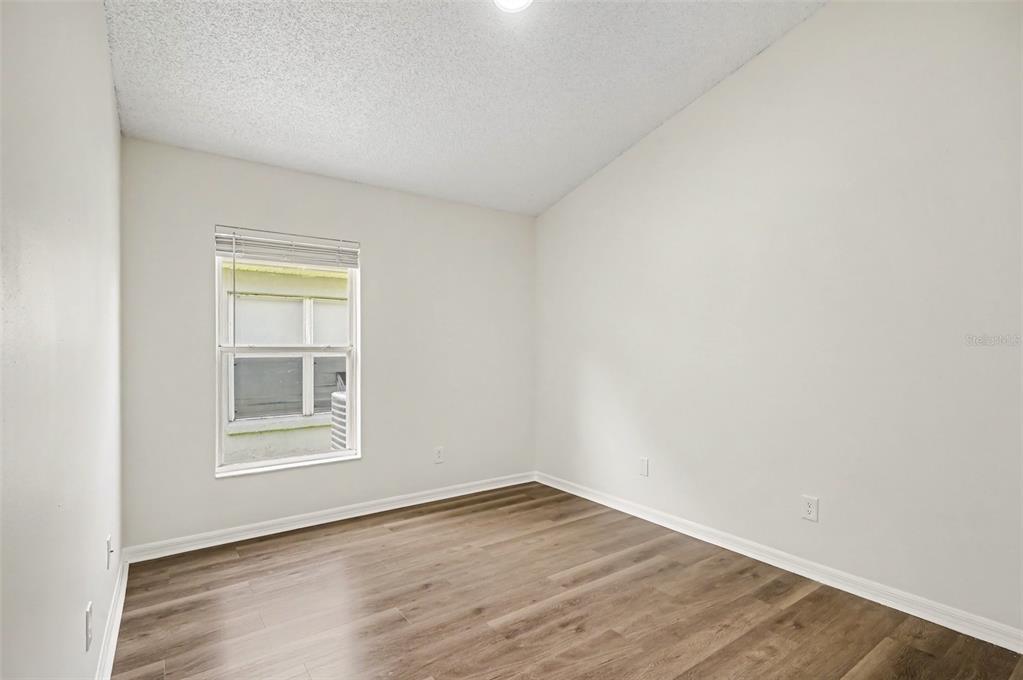An empty bedroom features light-colored walls, wood-look flooring, and a single window with blinds — 10131 RIVERS TRAIL DRIVE, ORLANDO, FL
