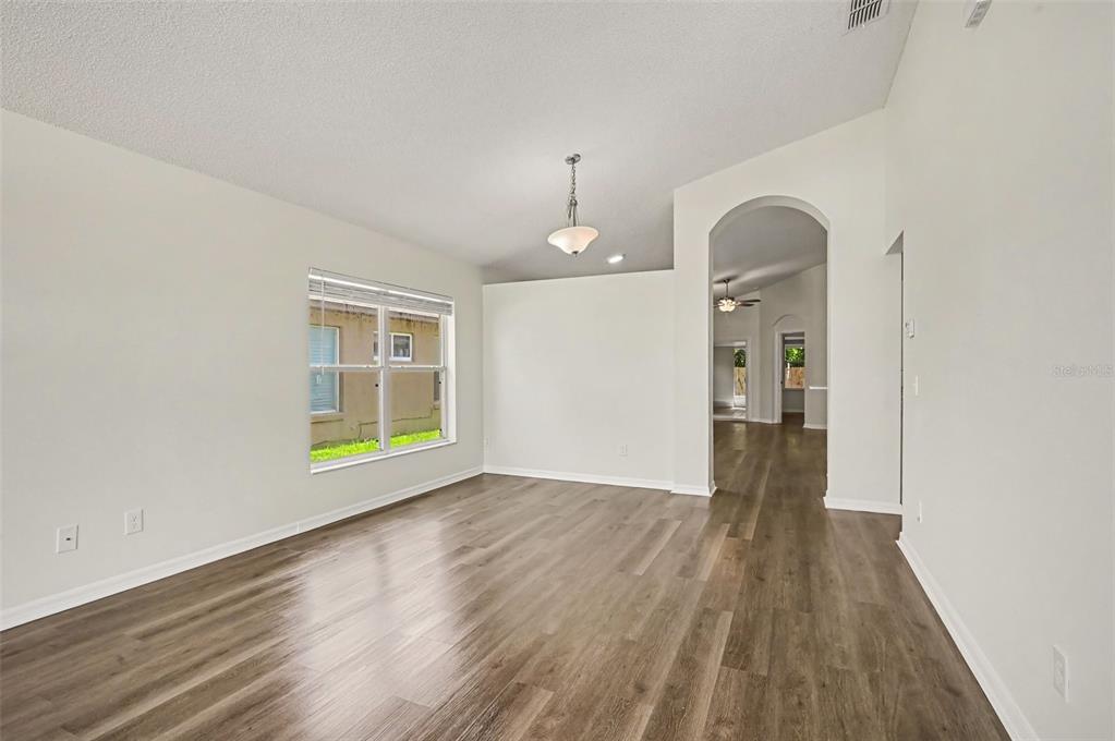 An empty room with light-colored walls, wood-look flooring, and an arched entryway to another room — 10131 RIVERS TRAIL DRIVE, ORLANDO, FL