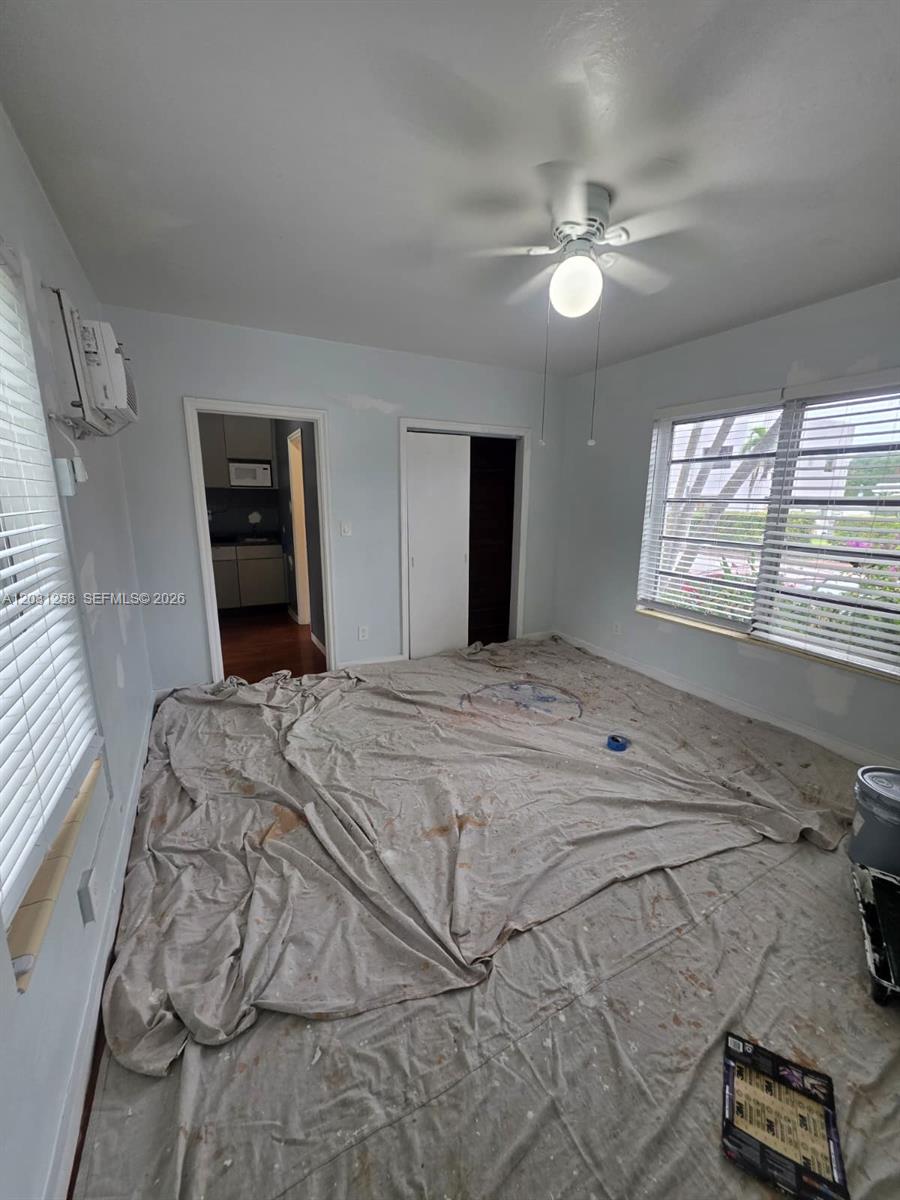 An empty bedroom features a ceiling fan, window blinds, and a drop cloth on the floor — 8024 Harding Ave # 1A, Miami Beach FL 33141, MIAMI BEACH, FL