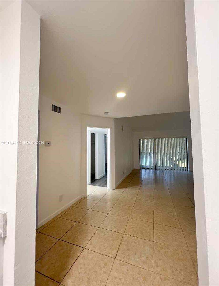 A tiled hallway leads toward a living area with sliding glass doors and vertical blinds — 8719 NW 39th St # 8719, Sunrise FL 33351, SUNRISE, FL