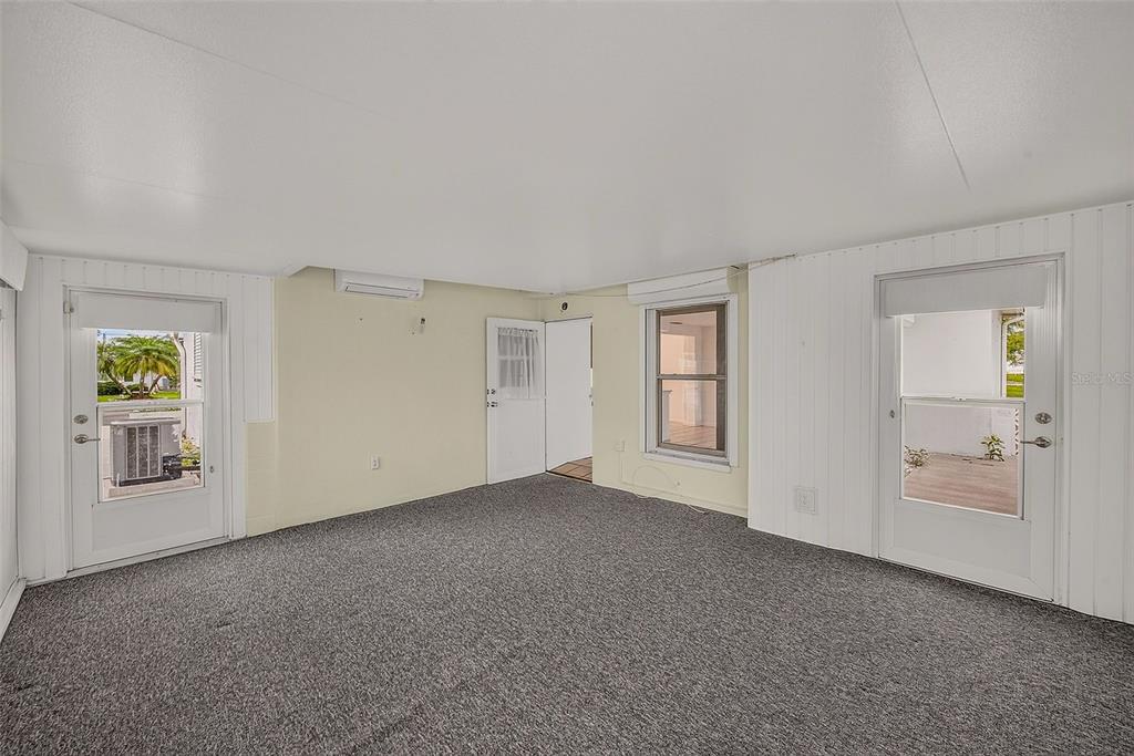 An interior room with gray carpet, white walls, two exterior doors, and a window — 14144 87TH AVENUE, SEMINOLE, FL